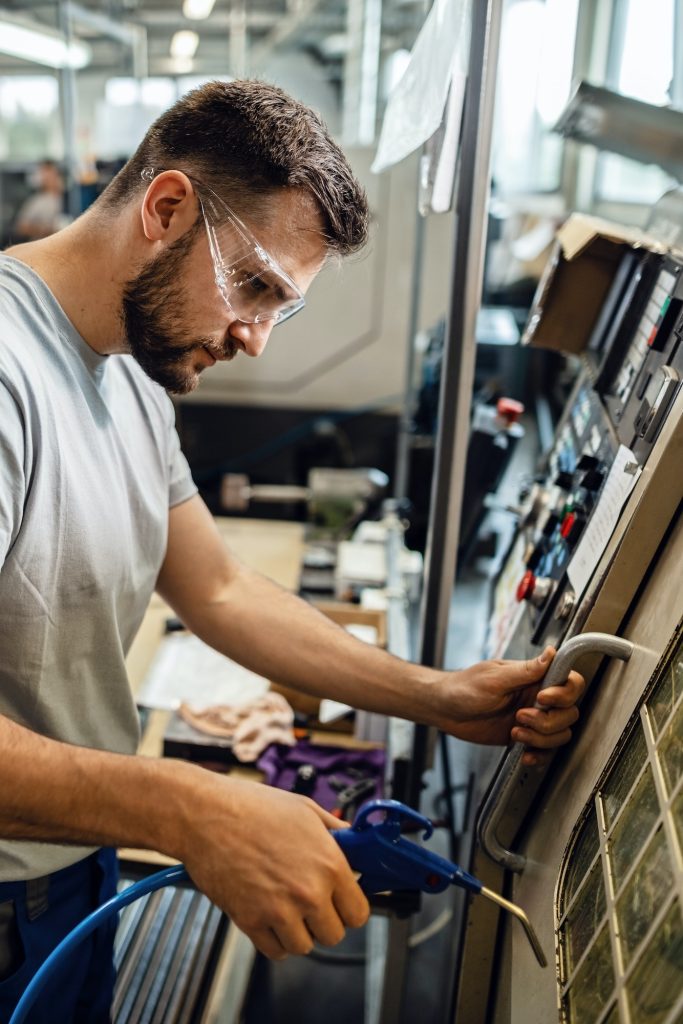 Manual worker working with CNC machine in a factory.